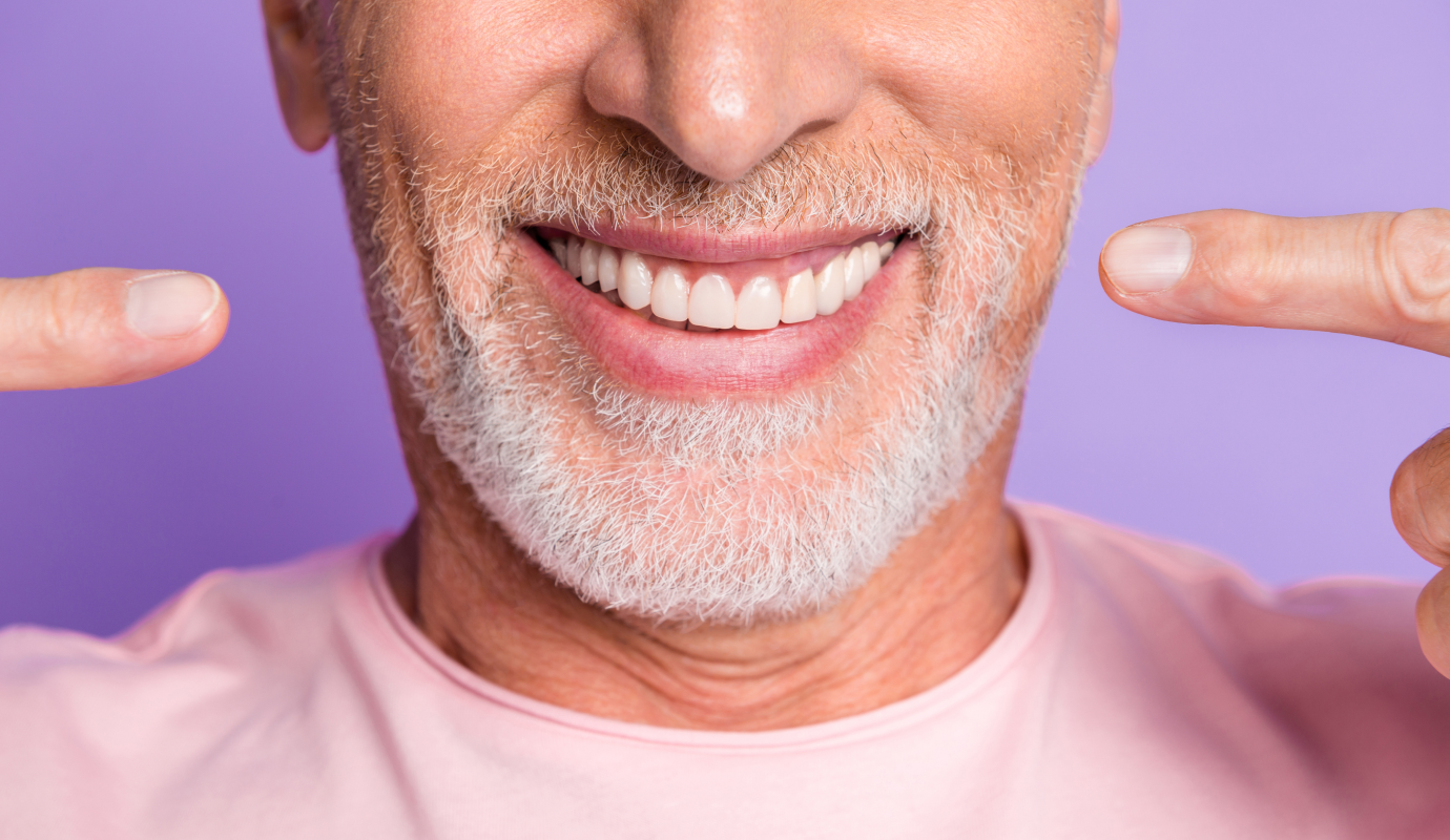 Patient satisfait montrant son sourire du doigt
