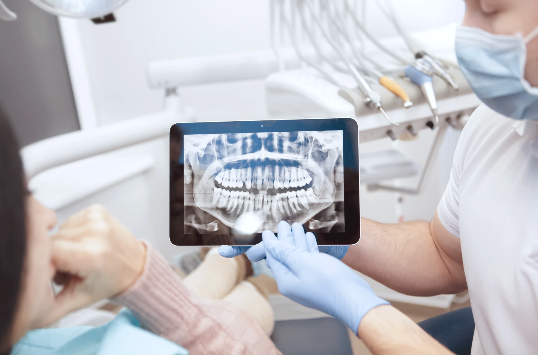 Praticien commentant une radiographie sur tablette avec sa patiente